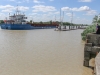 The size of the cargo ship is emphasised when it passes the pontoon